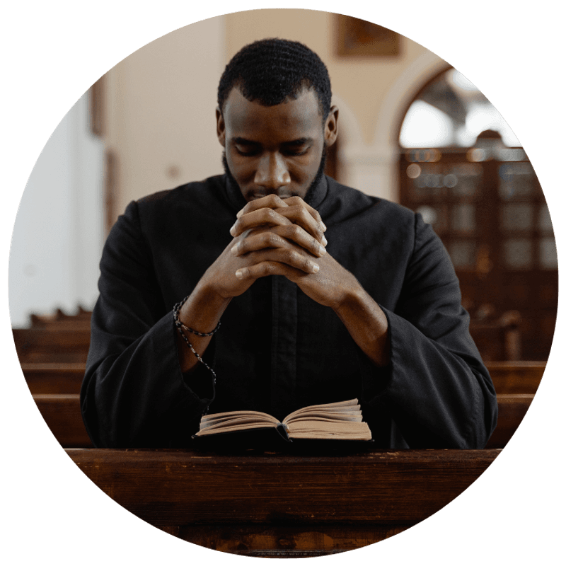 A person in quiet prayer with hands folded over an open book